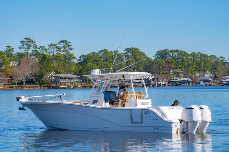 Slide: The Image of 2019 Sea Fox 328 Commander boat on calm water, surrounded by trees and houses. - 10