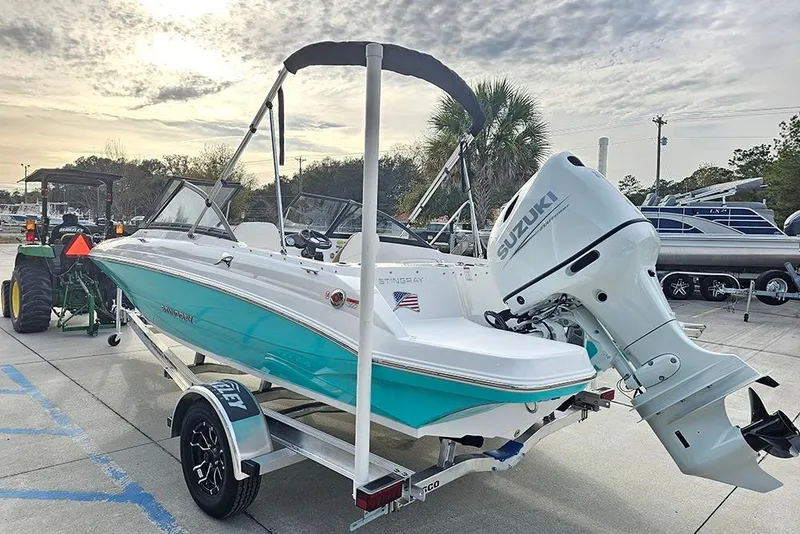 Slide: The Image of 2026 Stingray 191 DC boat on trailer, turquoise and white design, parked outdoors. - 6