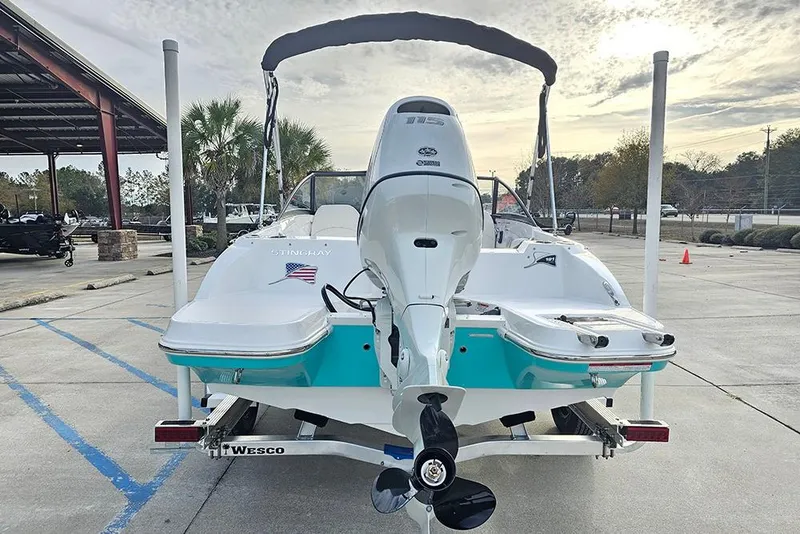 Slide: The Image of 2026 Stingray 191 DC boat with Suzuki outboard motor on trailer, parked outdoors. - 7