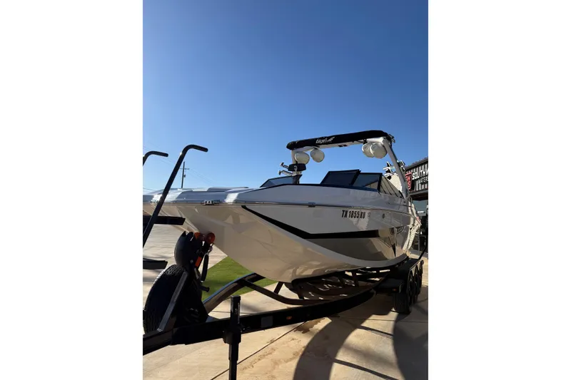 Slide: The Image of 2022 Tigé 24RZX boat on trailer under clear blue sky. - 10