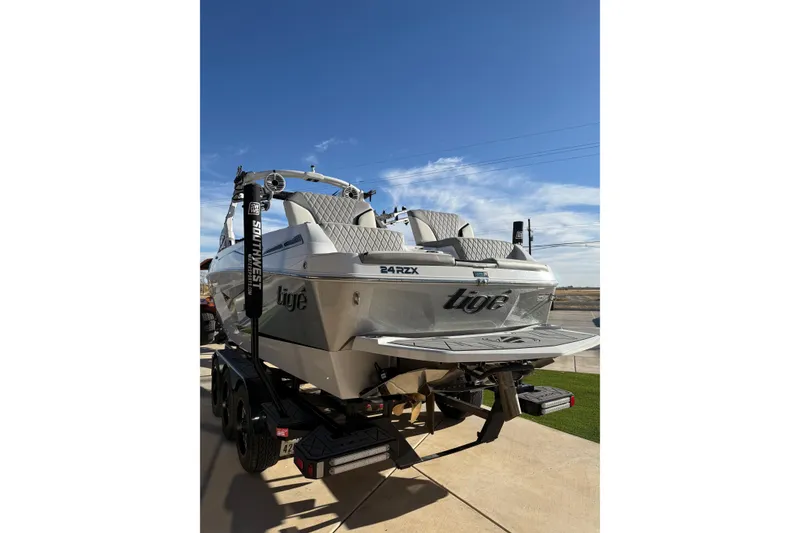 Slide: The Image of 2022 Tigé 24RZX boat on trailer under clear blue sky. - 7