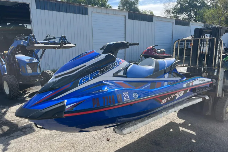 The Image of 2020 Yamaha WaveRunner GP1800R SVHO in blue, displayed outdoors near storage units. - 1