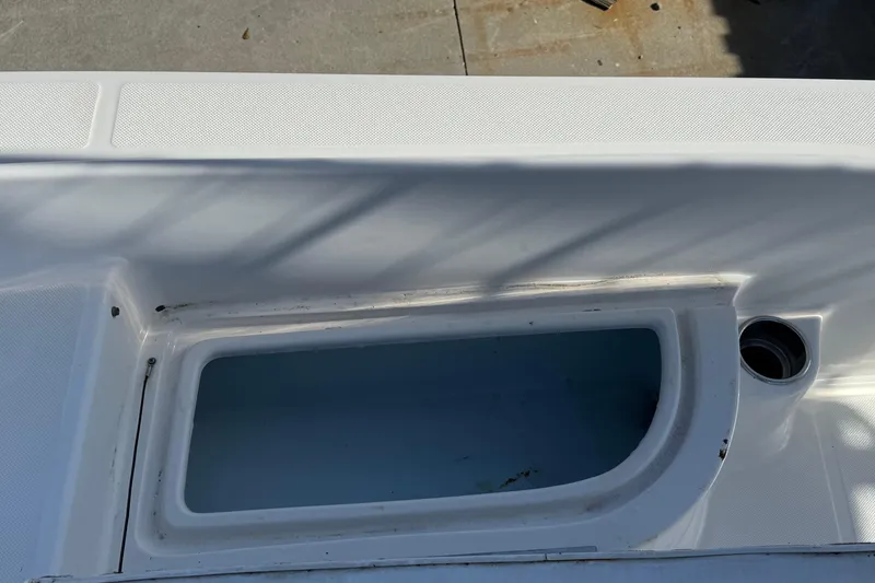 Slide: The Image of 2013 Sundance DX22 boat compartment with open storage area and drainage hole. - 11