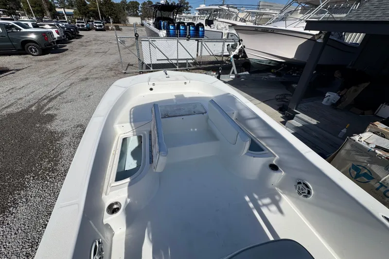 Slide: The Image of 2013 Sundance DX22 boat interior, white seating, and storage compartments in a marina setting. - 13