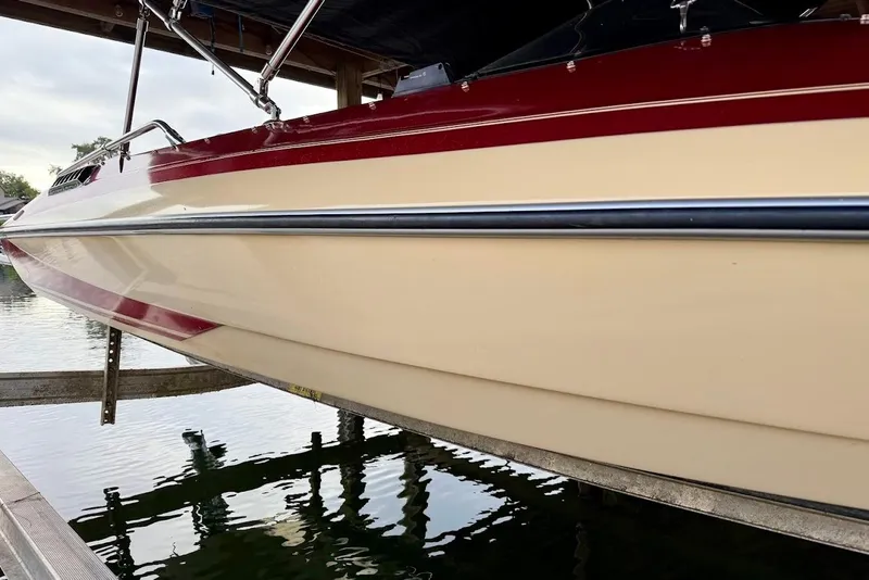 Slide: The Image of 1981 Glastron/Carlson C-512 boat with red and cream exterior, docked on water. - 16