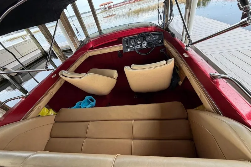 Slide: The Image of 1981 Glastron/Carlson C-512 boat interior with red and beige seating, docked by the water. - 36