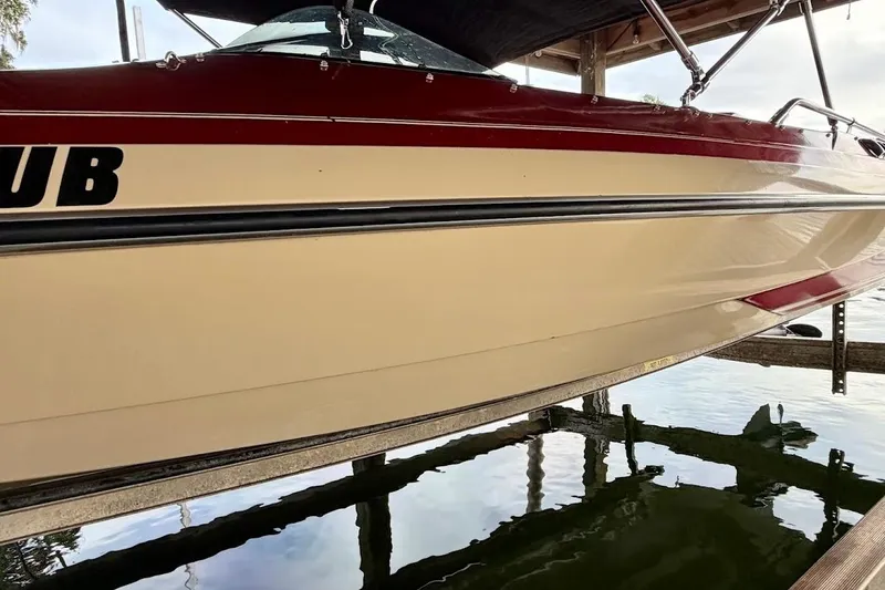 Slide: The Image of 1981 Glastron/Carlson C-512 boat with red and beige exterior, docked on calm water. - 4