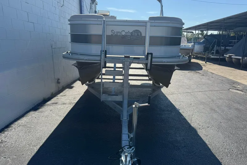 Slide: The Image of 2022 SunCatcher Select 16C pontoon boat on trailer in outdoor storage area. - 4