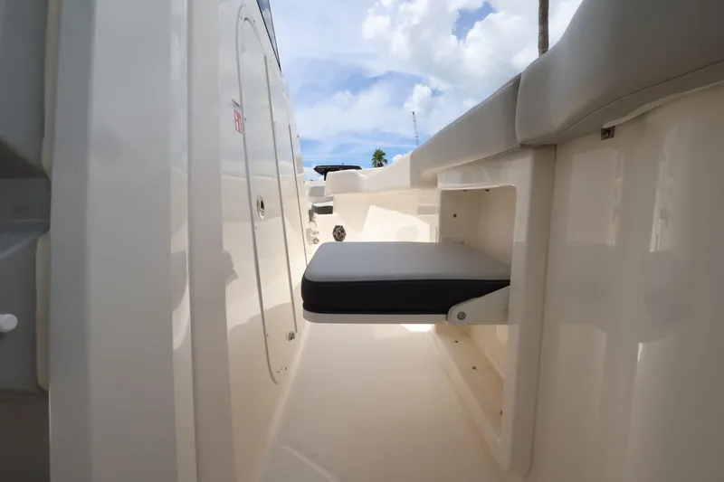 Slide: The Image of A seating area on a 2026 Boston Whaler 330 Outrage, featuring light upholstery and storage space. - 27