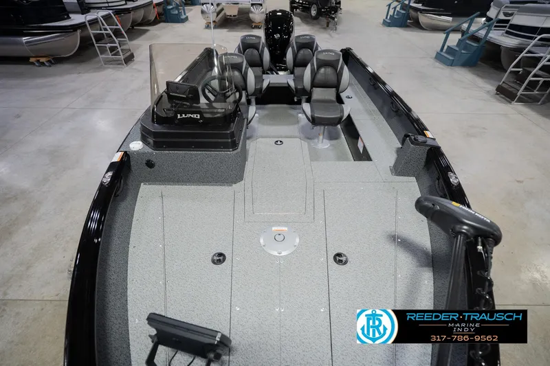 Slide: The Image of 2026 Lund 1700 Explorer SS boat interior in showroom, featuring seating and steering console. - 18