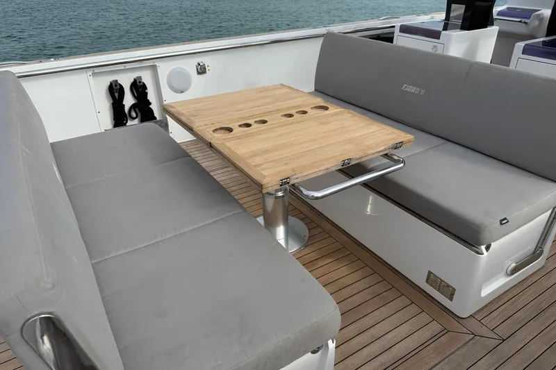 Slide: The Image of Luxury seating area on 2013 Fjord 40' Open yacht with wooden table and gray cushions. - 86