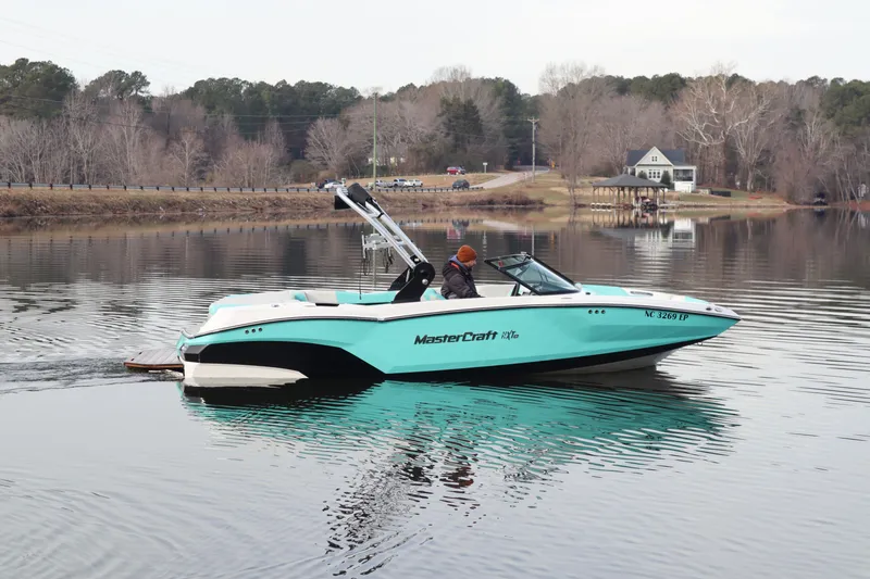 The Image of 2020 MasterCraft NXT22 boat on a calm lake with scenic background. - 0