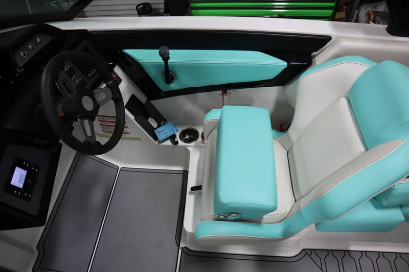Slide: The Image of 2020 MasterCraft NXT22 boat interior with turquoise and white seating, steering wheel, and controls. - 10