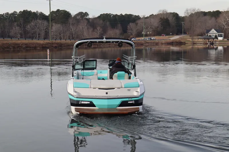 Slide: The Image of 2020 MasterCraft NXT22 boat cruising on a calm lake with scenic background. - 3