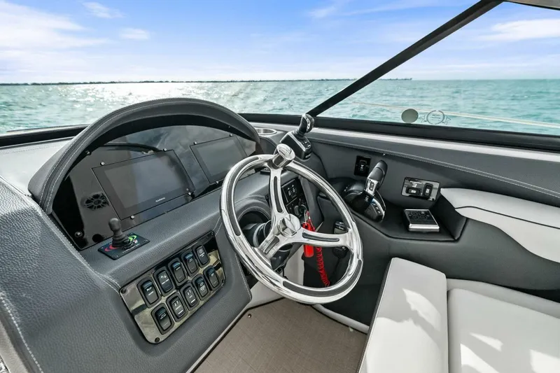 Slide: The Image of 2023 Regal 29 OBX boat dashboard with steering wheel and control panel, overlooking the ocean. - 18