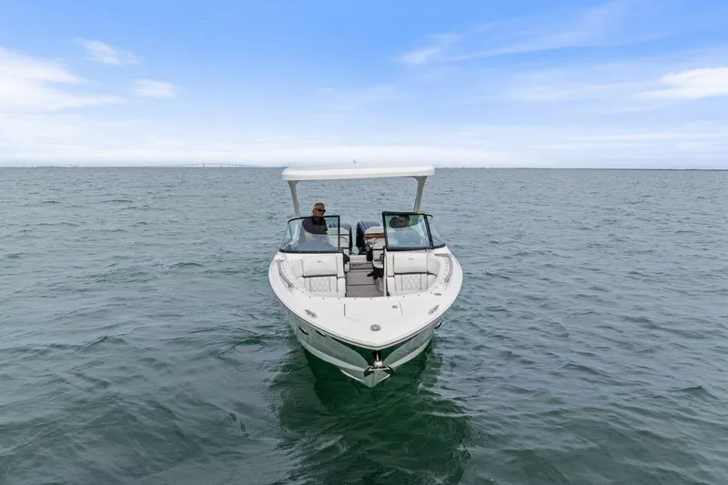 Slide: The Image of 2023 Regal 29 OBX boat cruising on open water under a clear sky. - 38