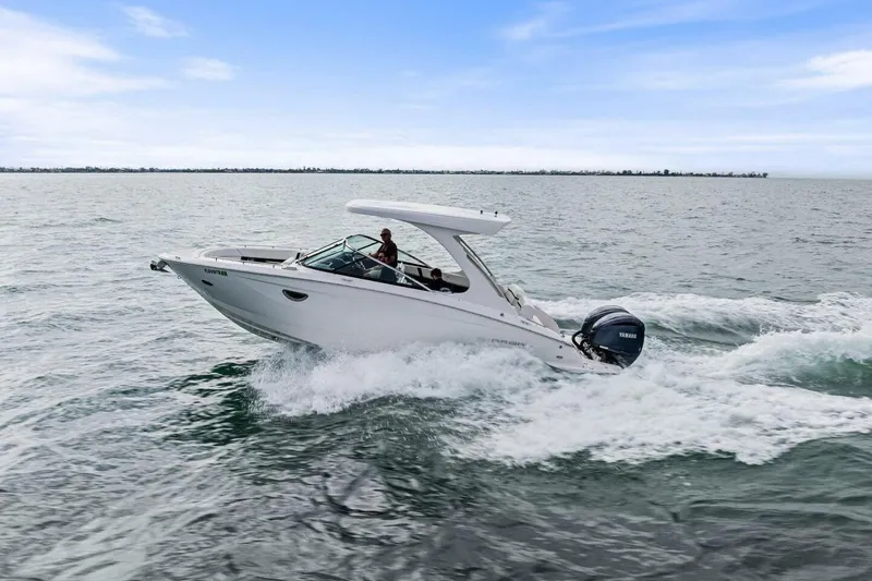Slide: The Image of 2023 Regal 29 OBX boat cruising on open water under a clear sky. - 44