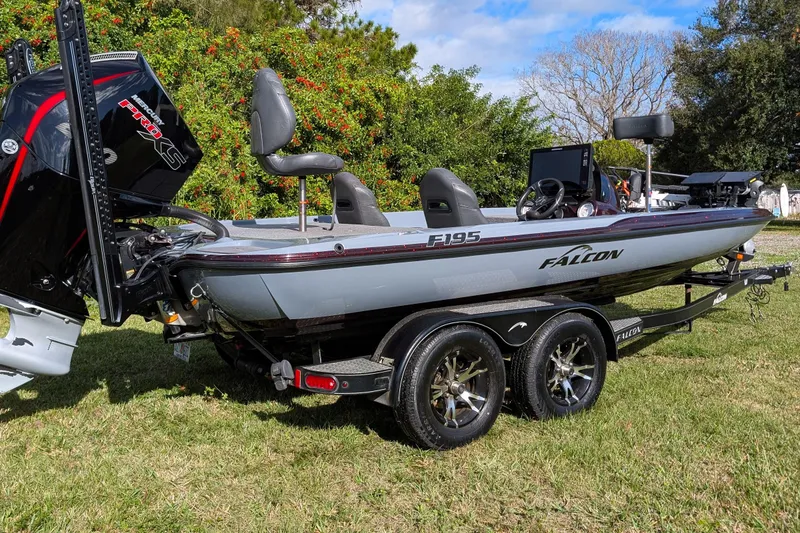 Slide: The Image of 2023 Falcon F195 boat on trailer, parked on grass with trees in background. - 3