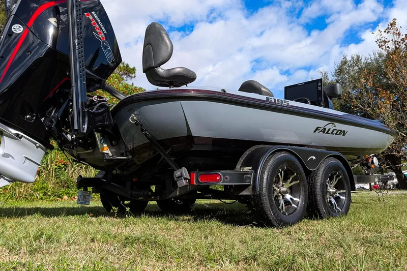 Slide: The Image of 2023 Falcon F195 boat on trailer, parked on grass with lush greenery background. - 5