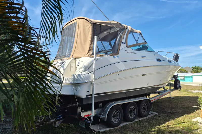 Slide: The Image of 2001 Sea Ray Sundancer 280 boat on trailer, parked outdoors under clear blue sky. - 4