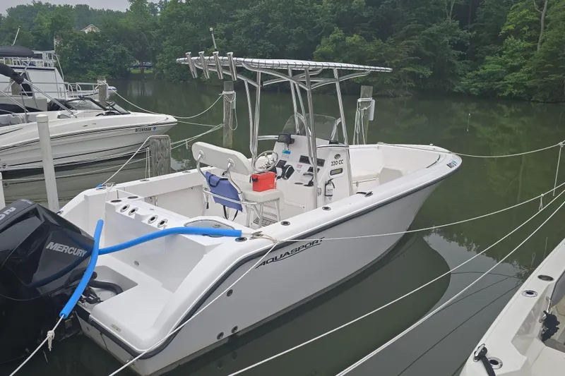 Slide: The Image of 2024 Aquasport 2200 Center Console boat docked on a calm lake. - 5