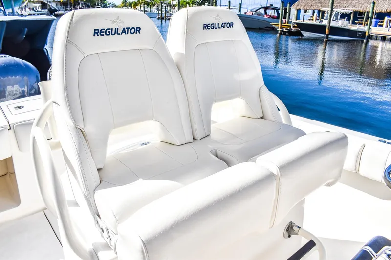 Slide: The Image of 2014 Regulator 28 boat with white leather seats, docked by the water. - 7