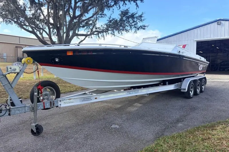 Slide: The Image of 1983 Cigarette 24' Classic boat on trailer, parked outdoors near a warehouse. - 2