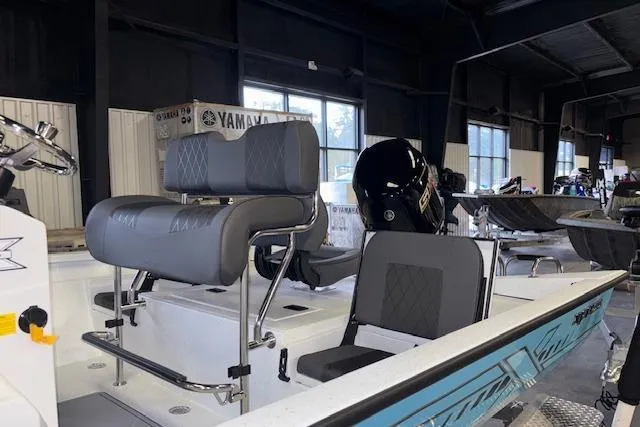 Slide: The Image of 2026 Xpress H20B Bay boat interior with seating and motor in showroom. - 5