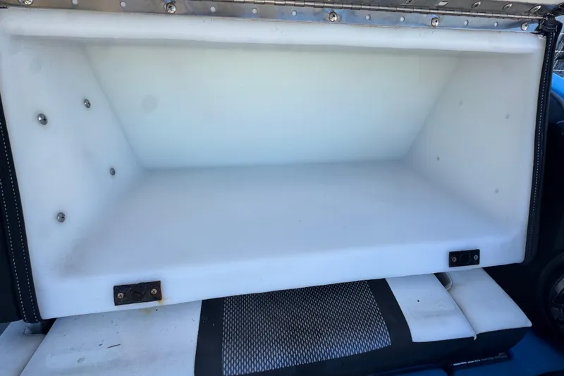 Slide: The Image of Open storage compartment in 2022 Yamaha Boats 255XD, featuring white interior and metal fasteners. - 75