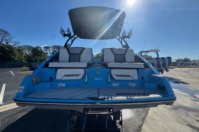 Slide: The Image of 2022 Yamaha Boats 255XD, blue exterior, rear view, parked outdoors under sunny sky. - 8