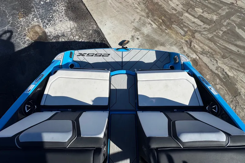 Slide: The Image of 2022 Yamaha Boats 255XD, blue and white seating, rear view on dock. - 83