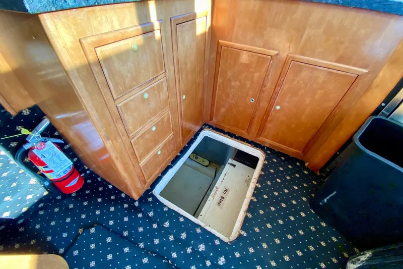 Slide: The Image of Wooden cabinet with open floor hatch, fire extinguisher, and patterned carpet in a 2001 SportsCat 44. - 107