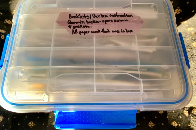 Slide: The Image of Plastic storage box labeled for booklets and paperwork organization. - 123