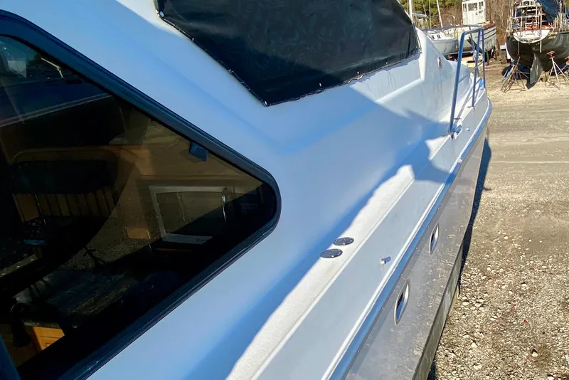 Slide: The Image of 2001 SportsCat 44 boat side view with windows and railing in a sunny setting. - 32