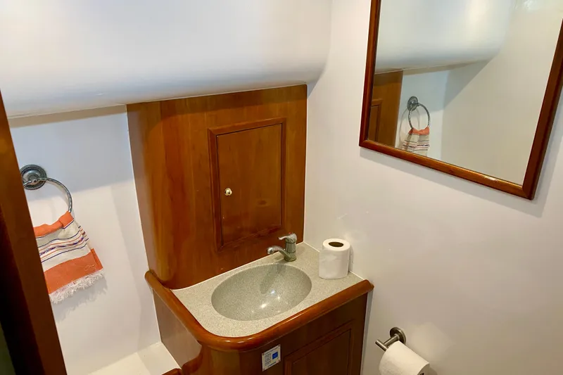 Slide: The Image of Small bathroom with wooden cabinetry, mirror, and sink in 2001 SportsCat 44 boat. - 77