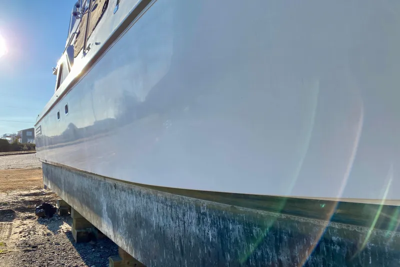 Slide: The Image of 2001 SportsCat 44 boat on dry dock, sunlit hull with visible wear. - 8