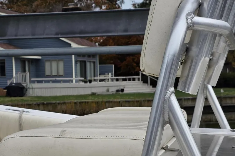 Slide: The Image of Close-up of a 2014 Mako 234 Center Console boat seat with a house in the background. - 2