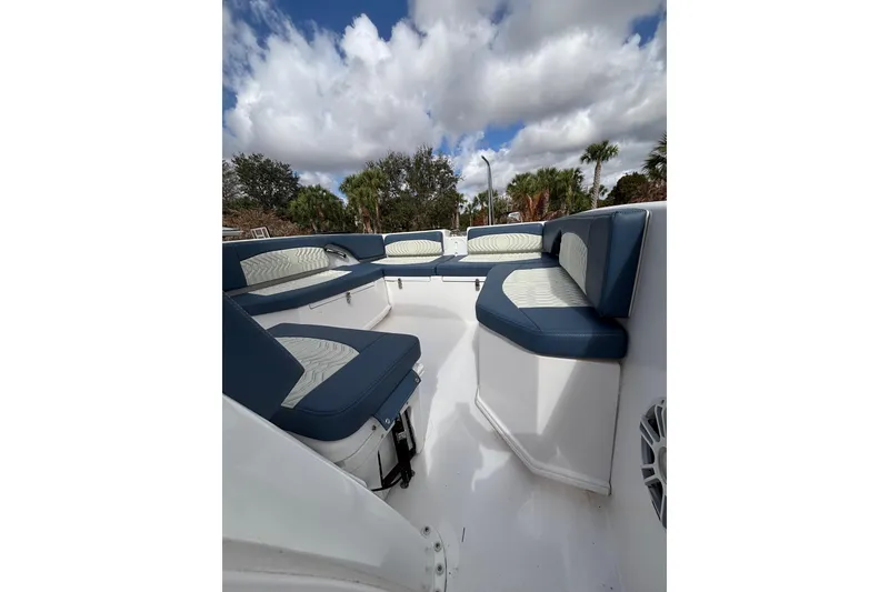 Slide: The Image of 2025 Twin Vee 260 GFX2 CC boat interior with blue and white seating under a cloudy sky. - 14