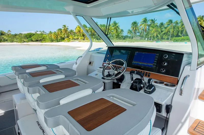 Slide: The Image of Manufacturer Provided Image: 2022 Regal 38 SAV boat cockpit with modern controls and tropical beach view. - 10