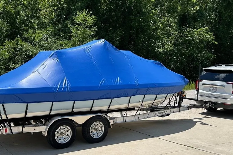 Slide: The Image of 2023 Skeeter SX210 boat covered with blue tarp on trailer, parked outdoors. - 15