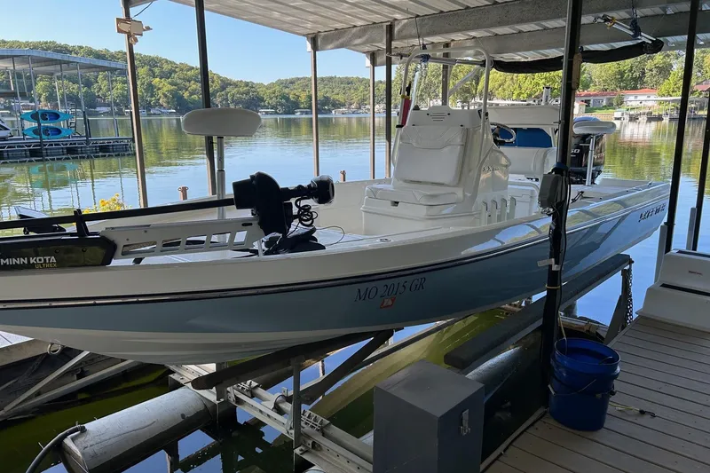 Slide: The Image of 2023 Skeeter SX210 boat docked on a serene lake under a covered slip. - 4