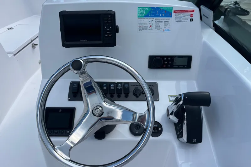 Slide: The Image of 2024 Aquasport 2200 Dual Console boat dashboard with steering wheel and control panel. - 6