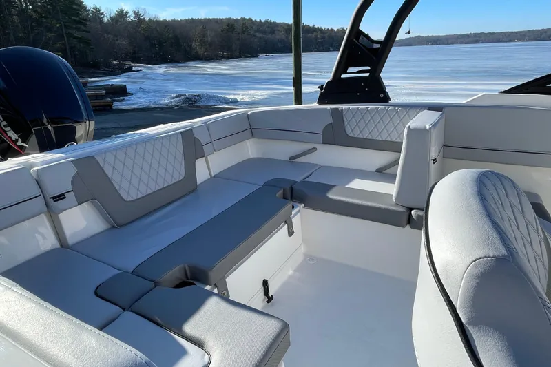 Slide: The Image of 2026 Bayliner VR4 Bowrider OB interior with gray seating, near a serene lake. - 16