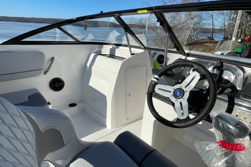 Slide: The Image of 2026 Bayliner VR4 Bowrider OB interior with steering wheel and seating, overlooking a serene lake. - 17
