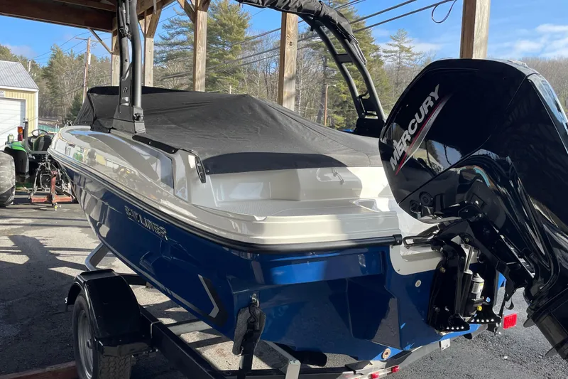Slide: The Image of 2026 Bayliner VR4 Bowrider OB with Mercury outboard engine, parked under a wooden shelter. - 2