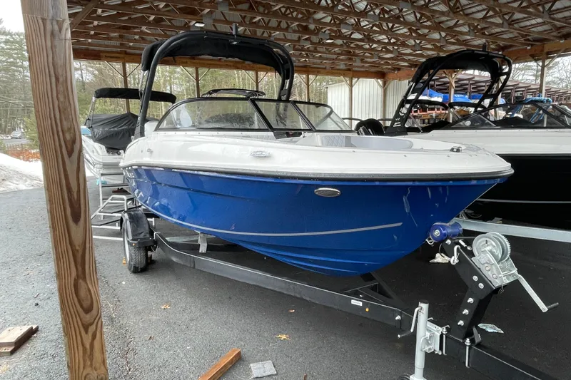 Slide: The Image of 2026 Bayliner VR4 Bowrider OB, blue hull, parked under a wooden shelter. - 3