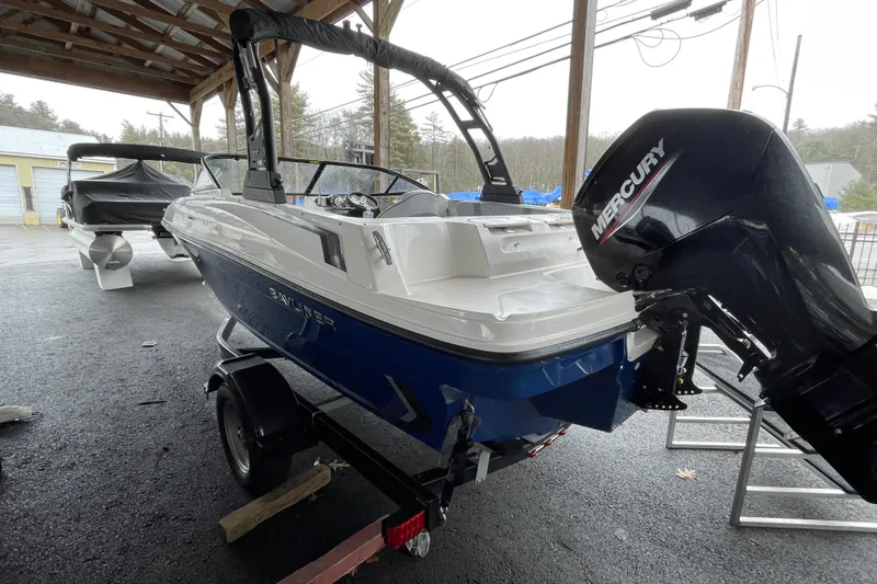 Slide: The Image of 2026 Bayliner VR4 Bowrider OB with Mercury outboard motor, parked under a shelter. - 6