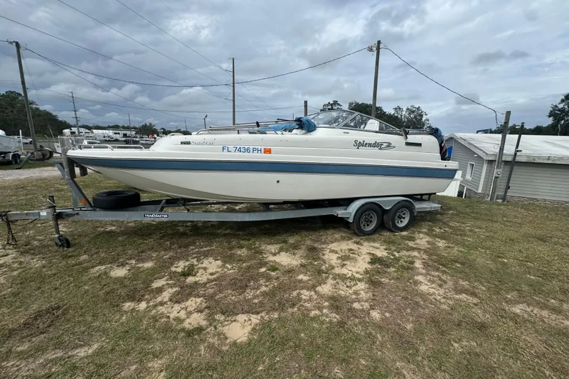Slide: The Image of 2012 Splendor 259 SUNSTAR boat on trailer, parked on grassy area under cloudy sky. - 12