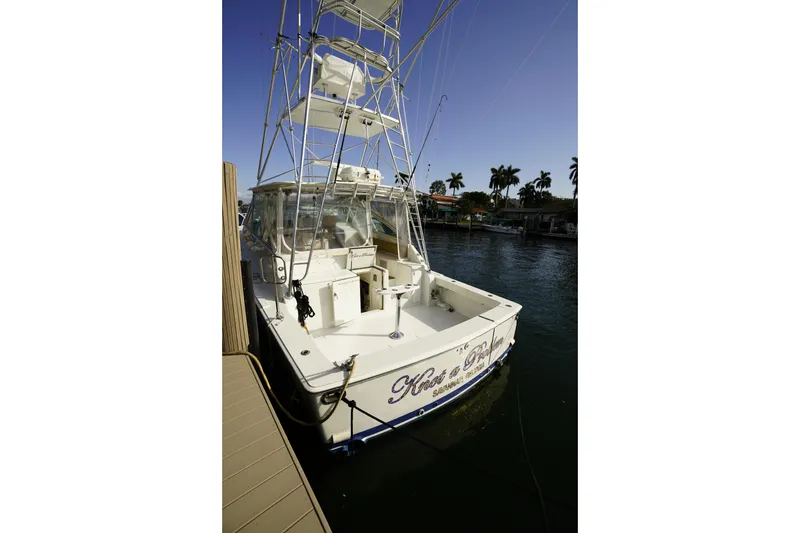 Slide: The Image of 1998 Viking Open Express 43 boat docked by palm trees under clear sky. - 4