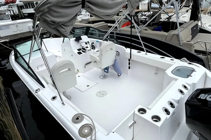 Slide: The Image of 2024 Aquasport 2200 Dual Console boat with spacious seating and modern design at a marina. - 5